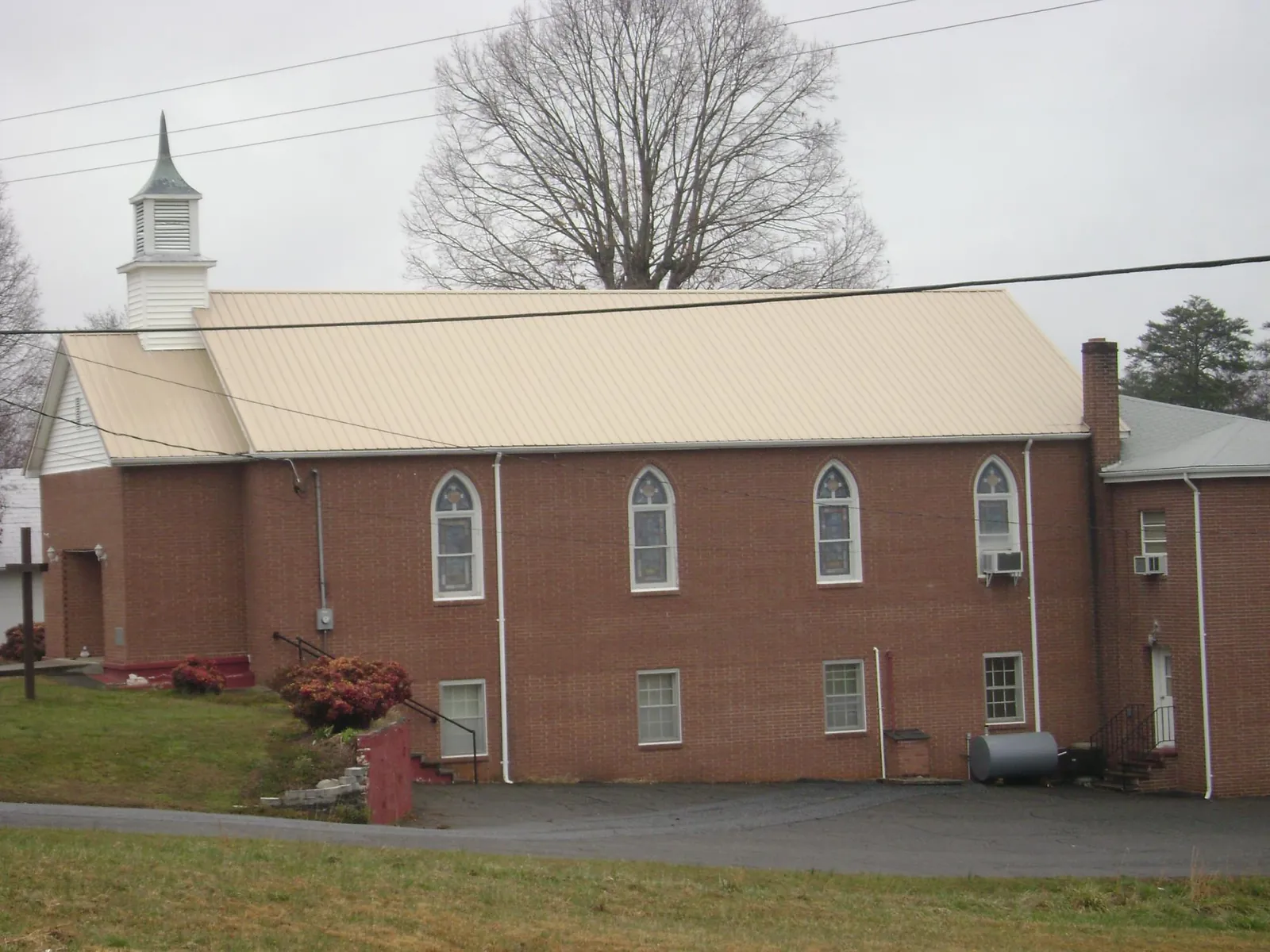 New tan metal roof on a brick church with a white steeple in Georgetown